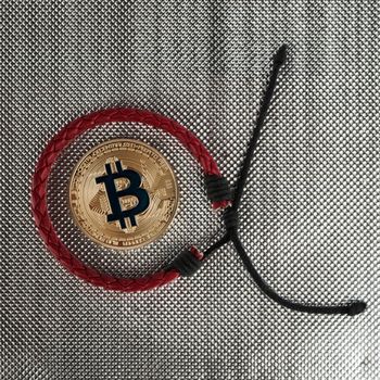 Digital currency physical gold bitcoin coin near red bracelet