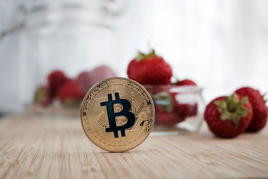 Cryptocurrency physical gold bitcoin coin near strawberries.