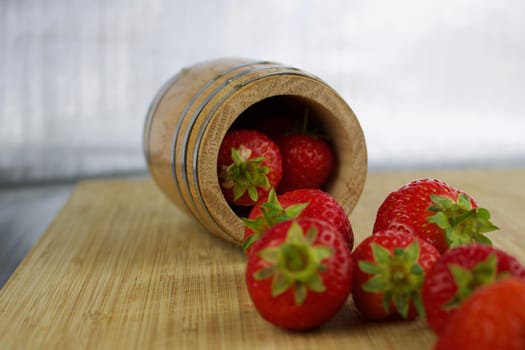 Wooden barrel with red strawberry on the wooden board.