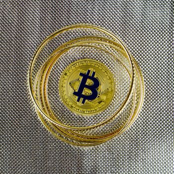 Cryptocurrency physical gold bitcoin coin near gold blink rings.