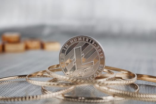 Cryptocurrency physical silver Litecoin coin near gold and gold rings