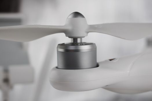 White drone arm with silver small engine and air screw on the top.
