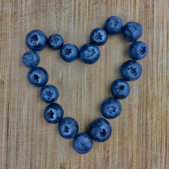 Fresh blueberry heart on the wooden kitchen board.