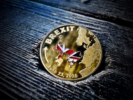 Gold brexit coin on the old wooden table