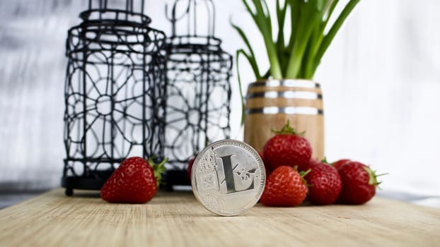 Digital currency physical silver Litecoin coin. Strawberry concept.