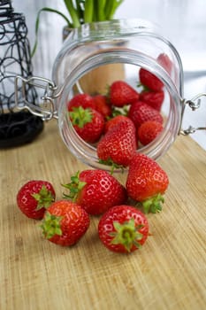 Red fresh strawberries in kitchen. Jar on the wooden board.