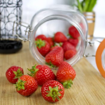 Red and fresh strawberries on the wooden board. Jar concept.