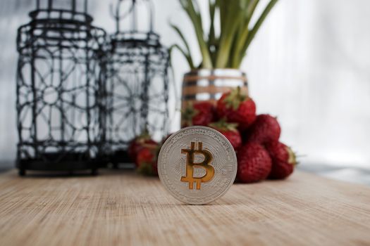 Cryptocurrency physical silver bitcoin coin, strawberry concept.