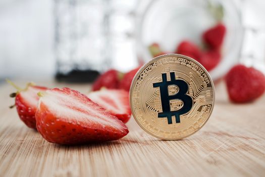 Digital currency physical gold bitcoin coin near fresh strawberries