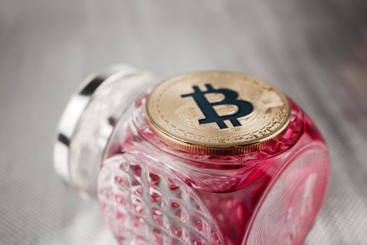 Cryptocurrency physical gold bitcoin coin on fragrance pink bottle