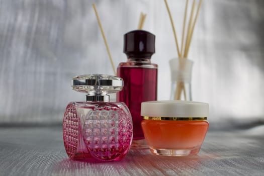 Pink perfume two bottles and orange creme on the table