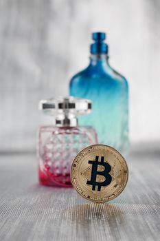 Cryptocurrency physical gold bitcoin coin near pink and green bottles.