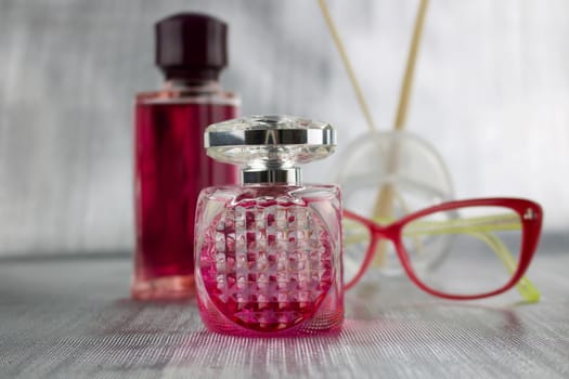 Pink glasses near pink perfume bottles on the table
