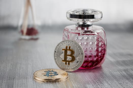 Cryptocurrency two physical bitcoin coins near pink bootle