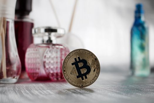 Digital currency physical gold bitcoin coin in pink perfume composition.