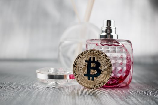 Cryptocurrency physical gold bitcoin coin near pink perfume bottle