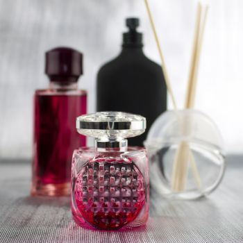 Two pink fragrance bottles near black big bottle