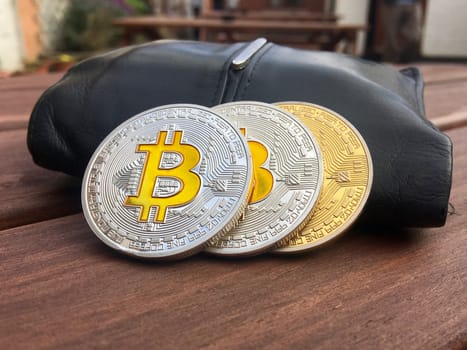 Cryptocurrency physical silver and brass bitcoin coins and black pocket on the table