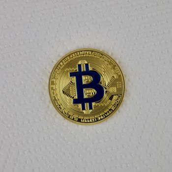 Digital currency physical gold bitcoin coin with a blue sign.