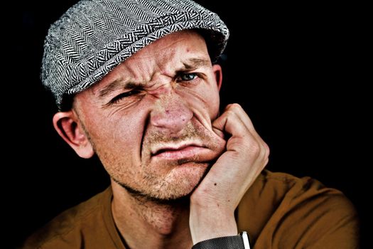 White sad man with a red face and grey cap.