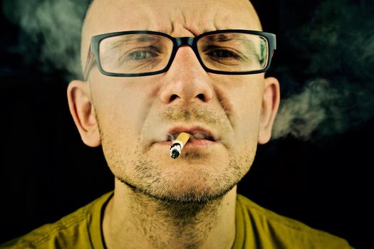 Young man in yellow tshirt smoking cigarette.