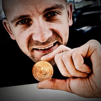 Cryptocurrency gold physical bitcoin in young man hand