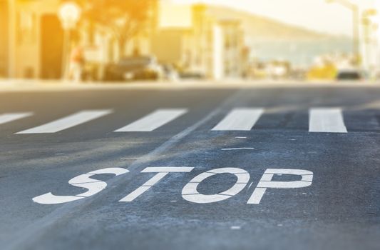 City crosswalk with symbol stop, closeup road texture with blurred San Francisco Bay in background in a warm sunny day