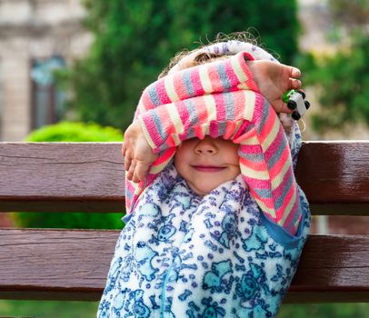 Little girl closes eyes with her hands. People