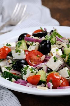 greek salad orzo pasta with black olive, red onion and cucumber, cherry tomatoes, feta and herbs. Vertically shot. foreground