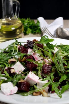 Salad from roasted beets, arugula, cheese feta, and walnuts. Vertical shot. Foreground close-up.