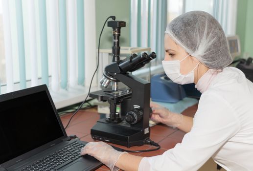 Women scientists exploring the biological sample by modern electron microscope in a laboratory