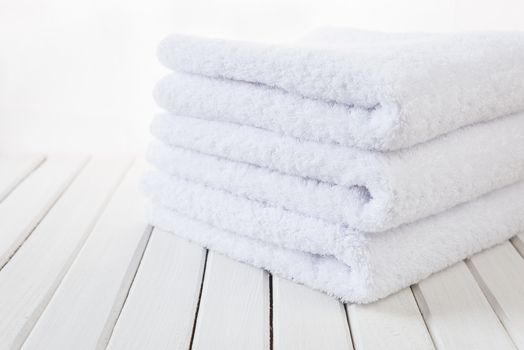 Stack of three white fluffy bath towels on the background of white boards