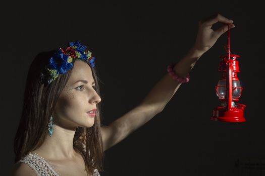 Portrait of a young woman in a wreath of flowers on a black background