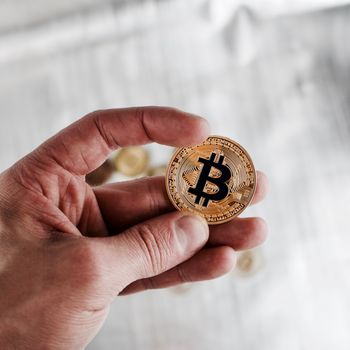 Cryptocurrency physical gold bitcoin coin in man hand.