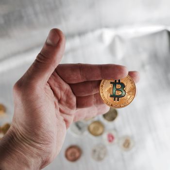 Digital currency physical gold bitcoin coin in man hand.