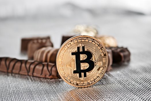 Cryptocurrency physical gold bitcoin coin and sweet chocolates.