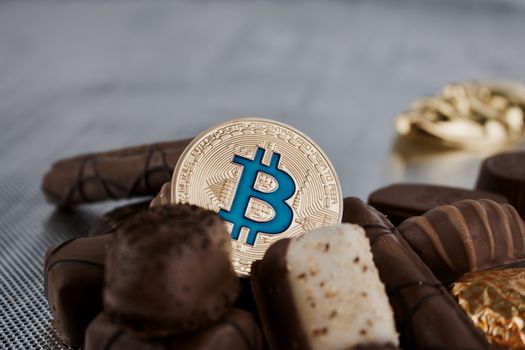 Digital currency physical blue bitcoin coin and chocolates.