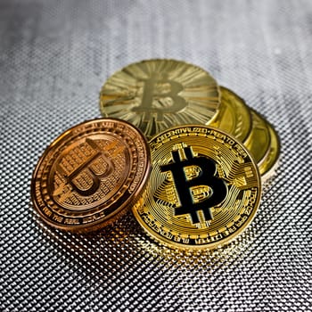 Digital currency physical gold and brass bitcoins on silver background.