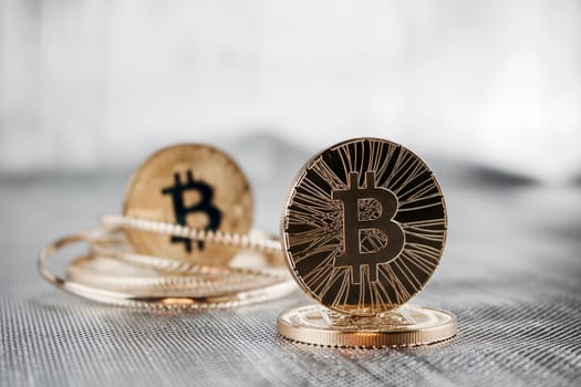 Digital currency physical gold bitcoin coins. Silver background.