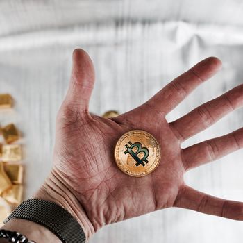 Cryptocurrency physical gold bitcoin coin on the hand.