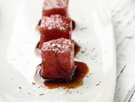 Tuna sashimi dipped in soy sauce,  thick salt and dill on old white wooden board. Raw fish in traditional Japanese style. Horizontal image.