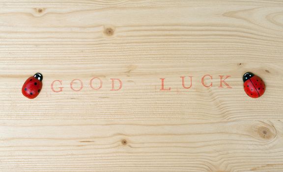 Stamped text Good luck on wood and ladybug, background