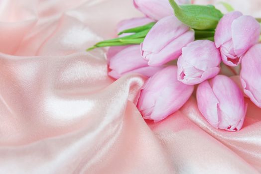 Bouquet of tulip flowers on a background of silk fabric; with copy-space