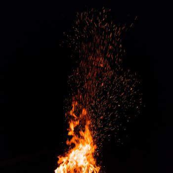 Campfire with flying sparks isolated on black background