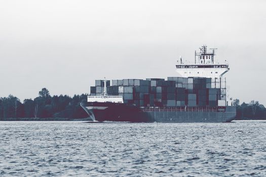 Full container ship moving to Baltic sea. Riga, Latvia