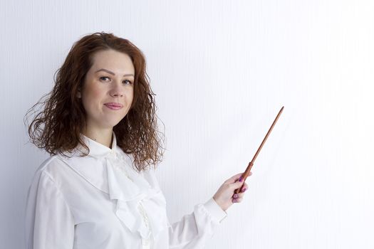 Young woman is pointing out something with a pointer on a blackboard