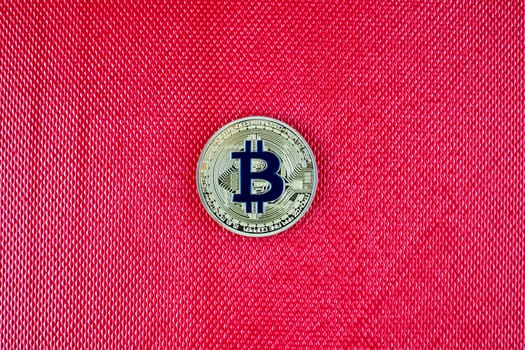 Cryptocurrency physical gold bitcoin coin on red scene. Blue bitcoin.
