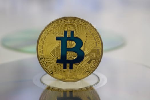 Digital currency physical gold bitcoin coin on CD. Financial concept.