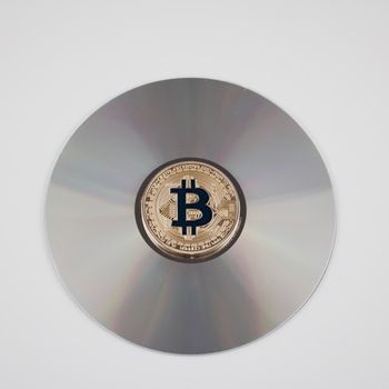 Digital currency physical gold bitcoin coin on the CD. Financial concept.