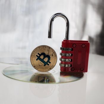 Digital currency physical gold bitcoin near red padlock on the CD
